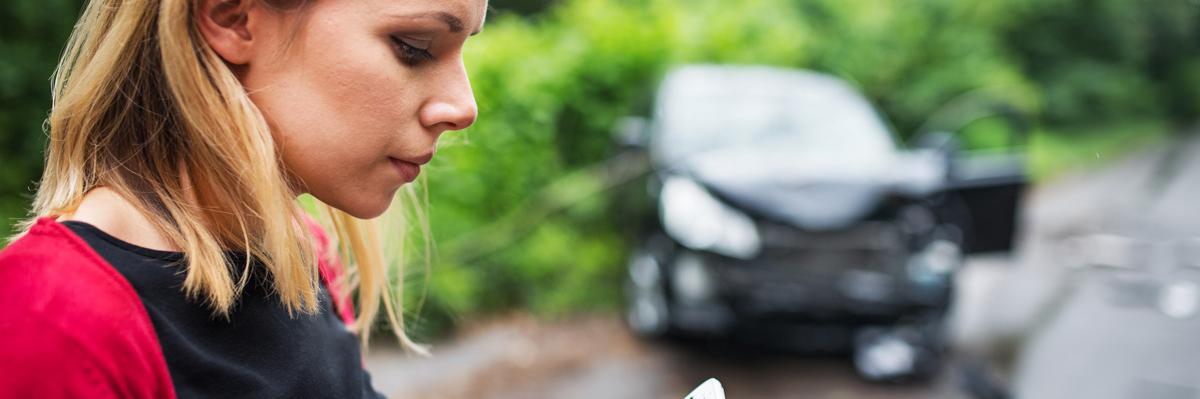 Young woman on the phone after after a car accident.