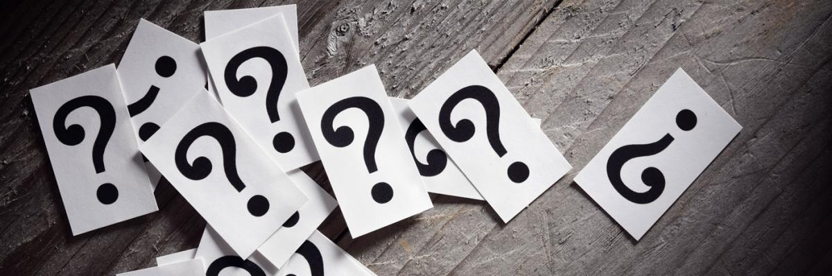 Paper cut outs of questions marks scattered on a wooden table