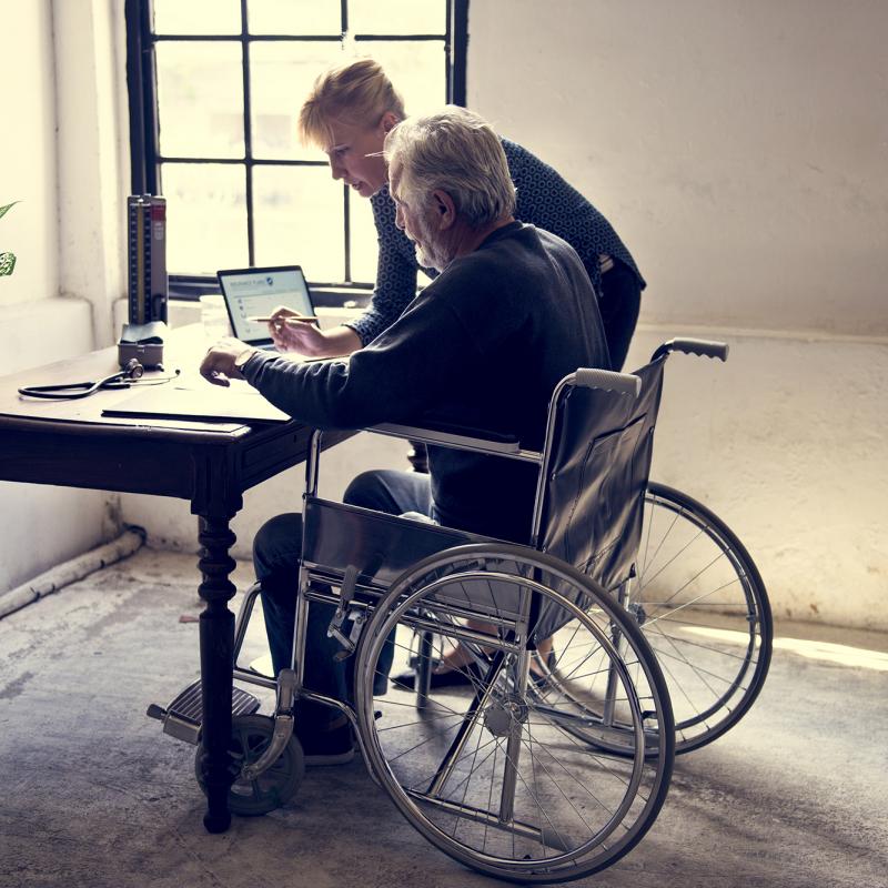 Man in wheelchair getting help picking life insurance